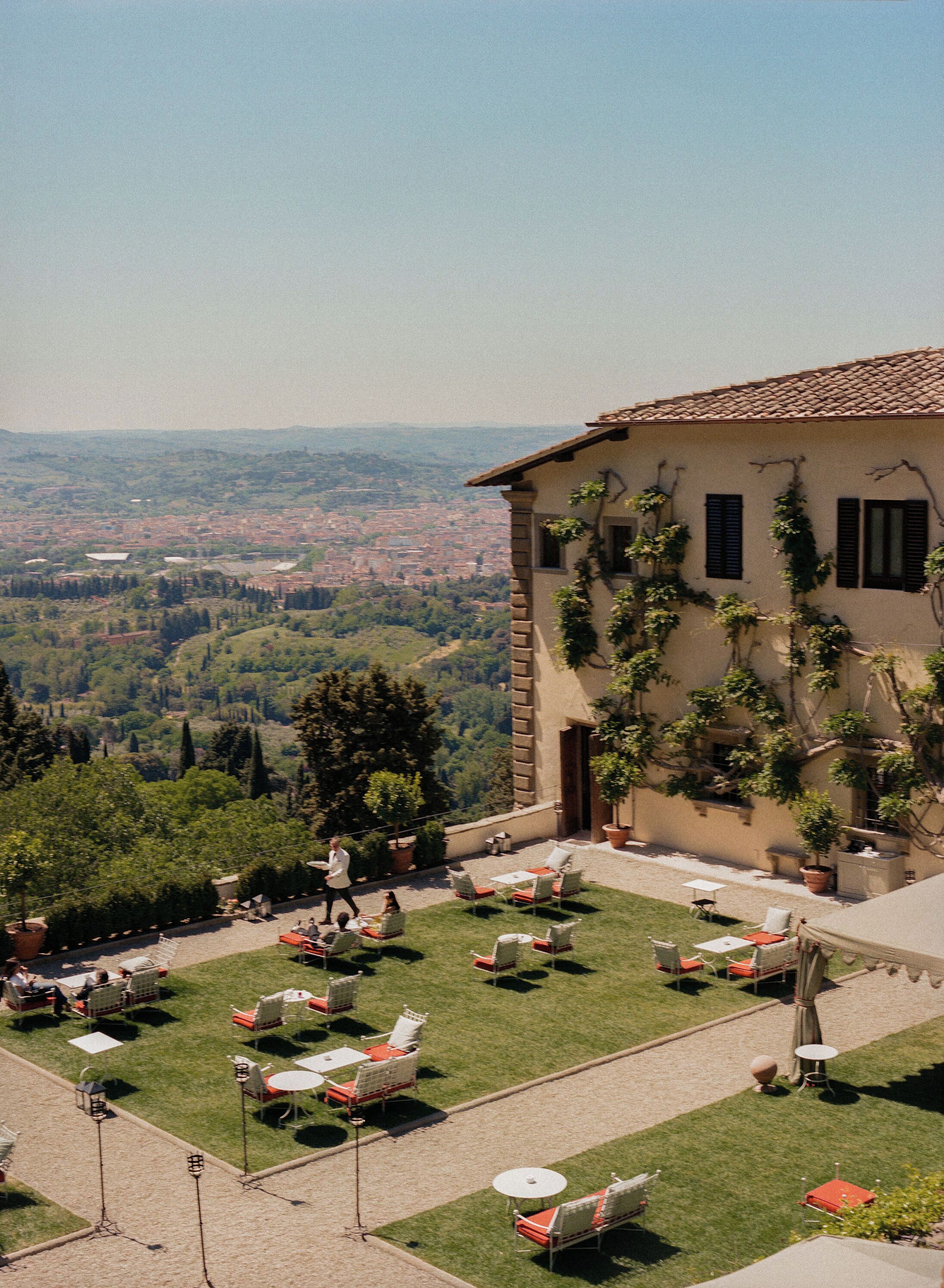 A villa with a terrace, outdoor seating, and a view of a valley.