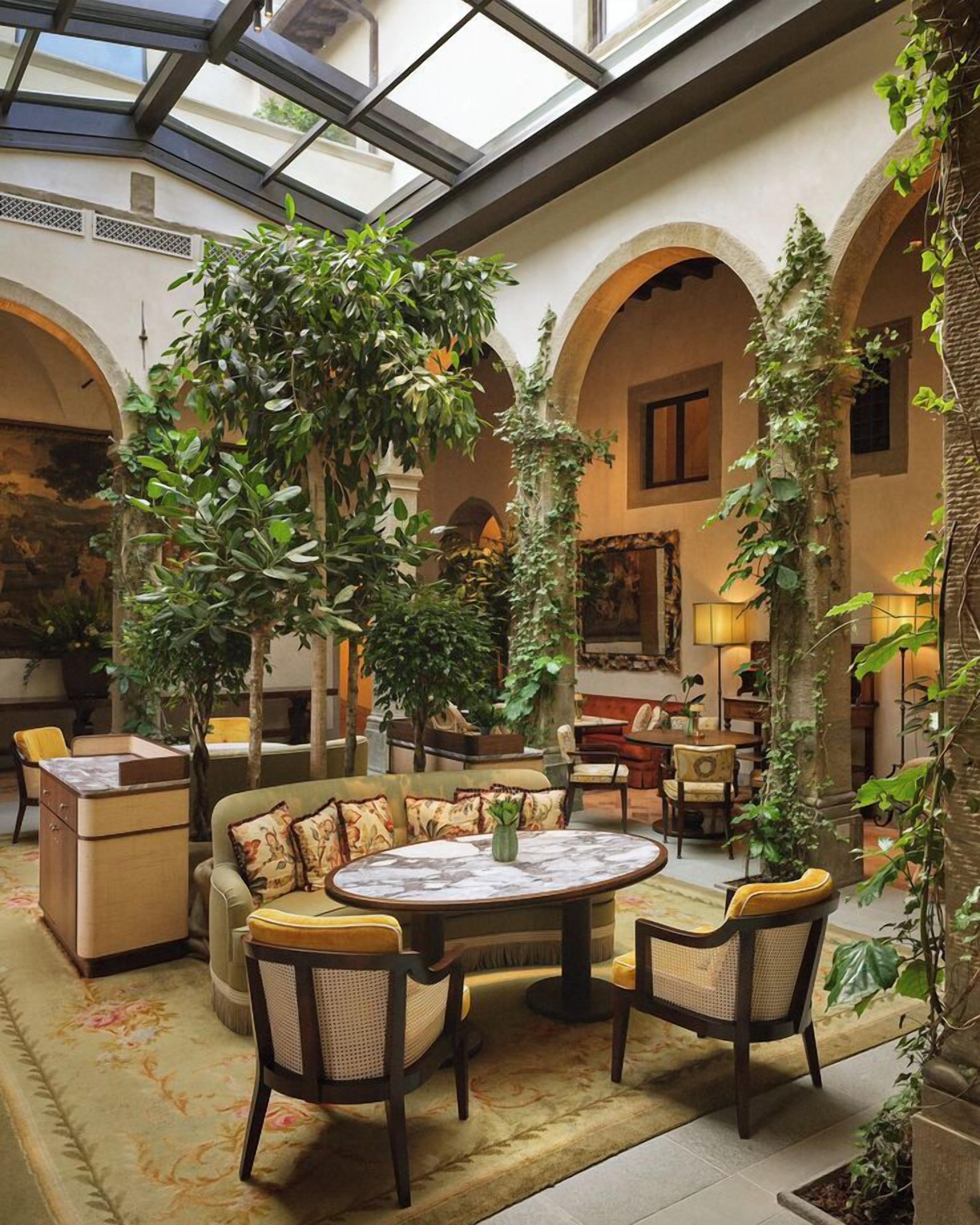 A spacious indoor area with a high ceiling, arched columns, and a central seating area with a round table and chairs.