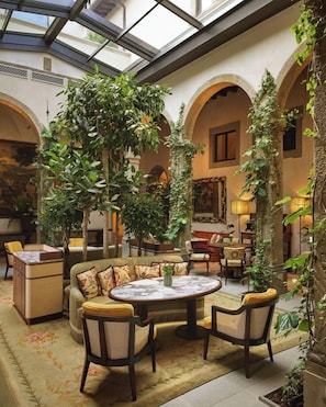 A spacious indoor area with a high ceiling, arched columns, and a central seating area with a round table and chairs. - Villa San Michele, A Belmond Hotel, Florence (Fiesole)