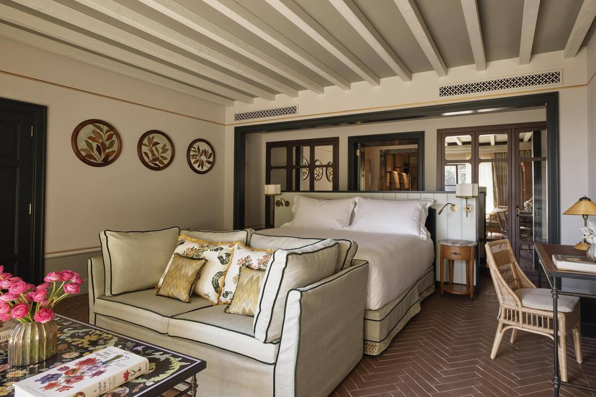 A hotel room with a bed, a sofa, a small table, and a chair.