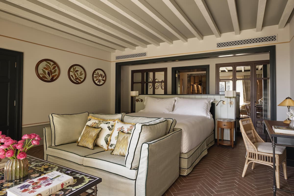 A hotel room with a bed, a sofa, a small table, and a chair.