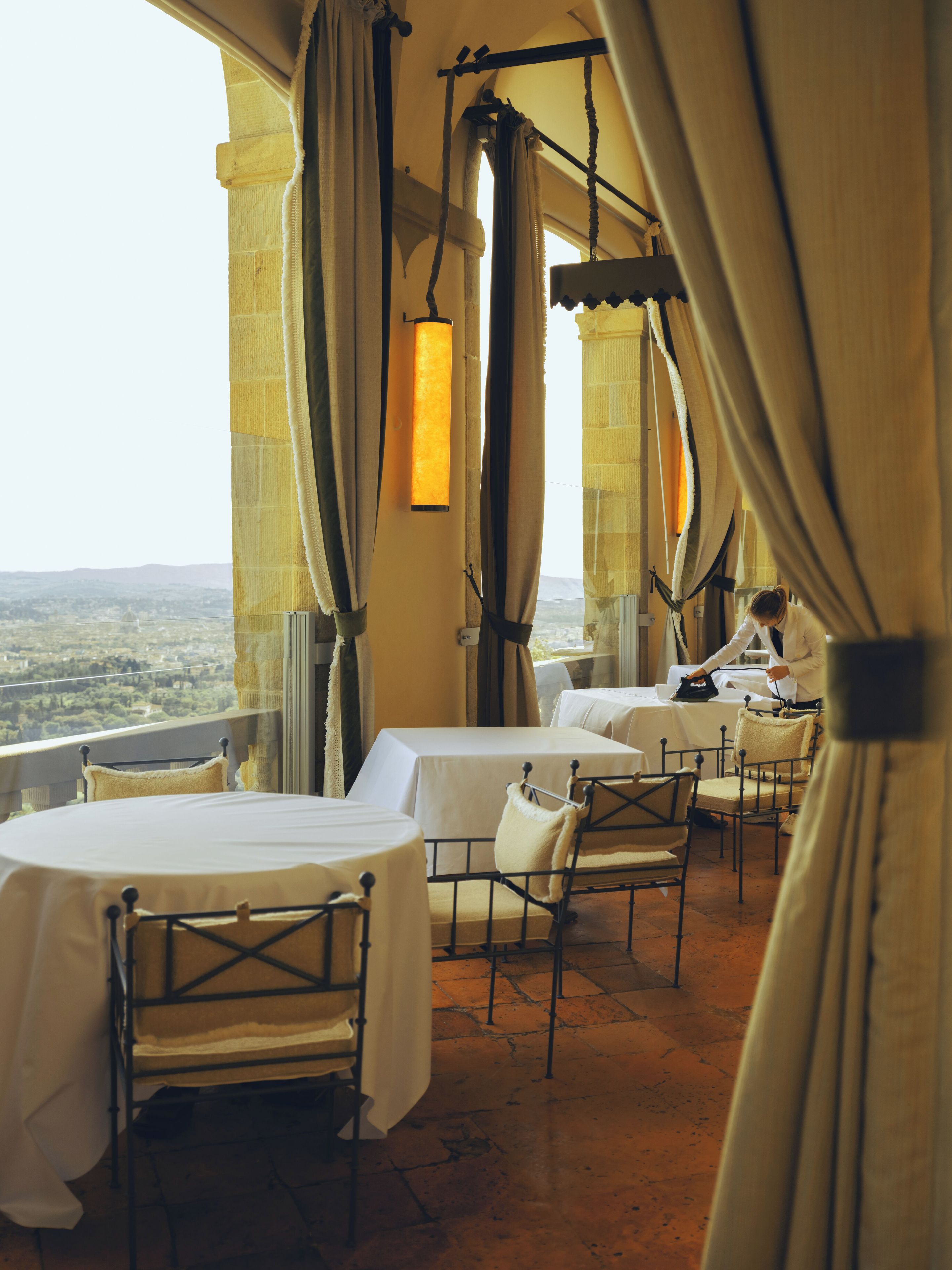 A room with a terrace overlooking a cityscape, featuring tables and chairs set up for dining.