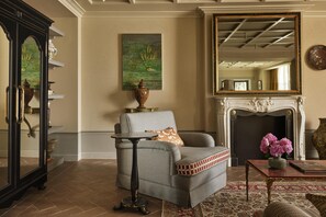 A living room with a sofa, a table, a fireplace, a mirror, and a painting on the wall. - Villa San Michele, A Belmond Hotel, Florence (Fiesole)