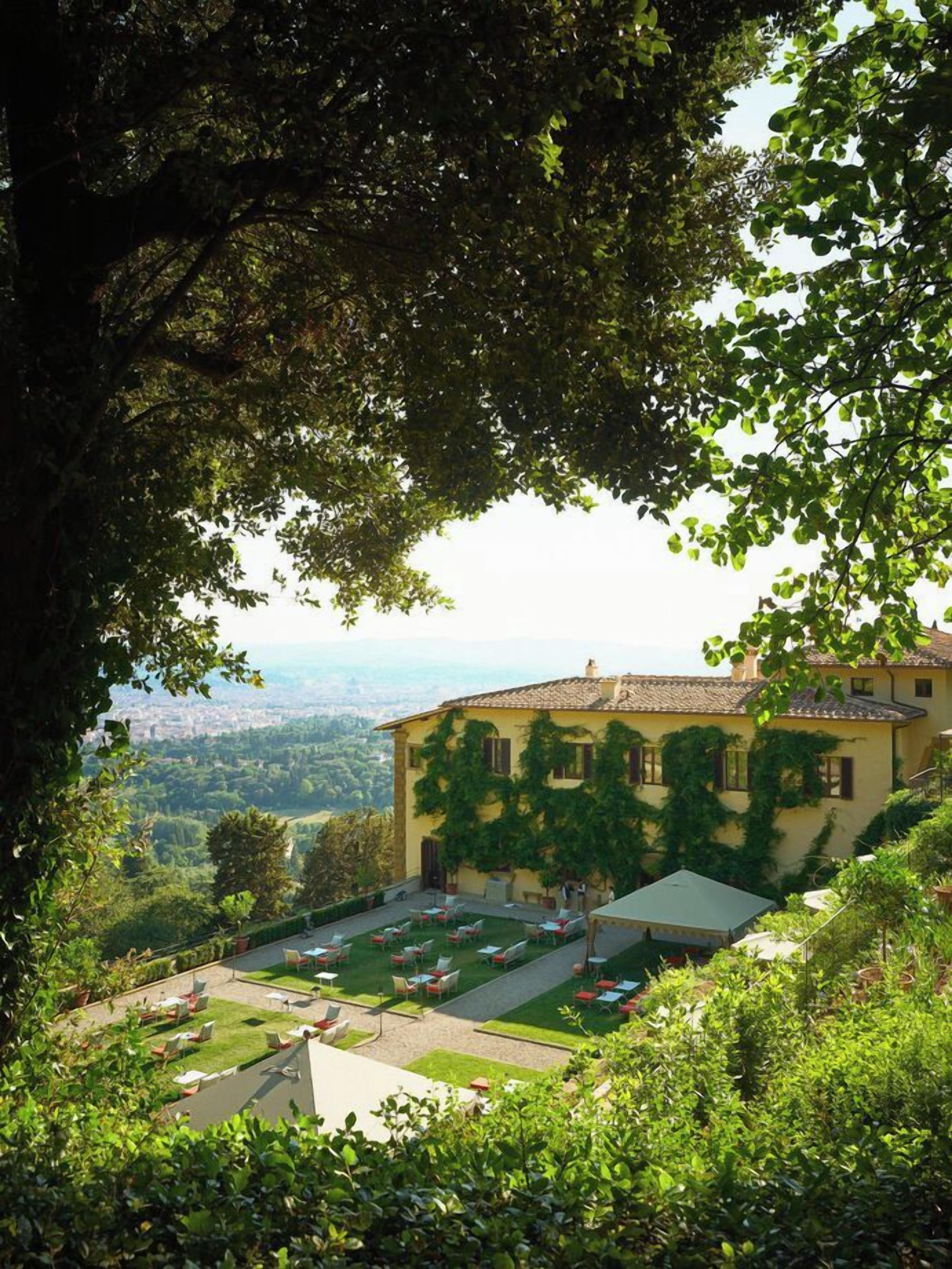 Un bâtiment doté d’un jardin et d’un espace extérieur aménagé pour s’asseoir, entouré d’arbres.