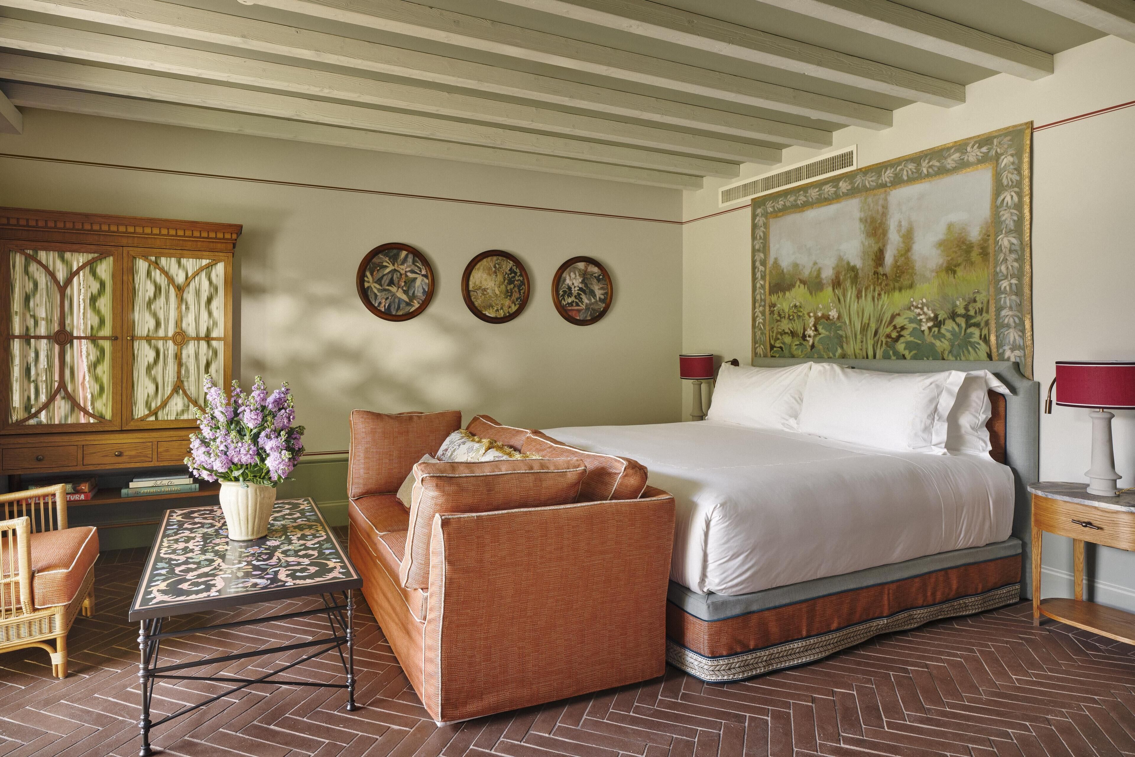 Un dormitorio con cama, sofá, mesa y un cuadro en la pared.