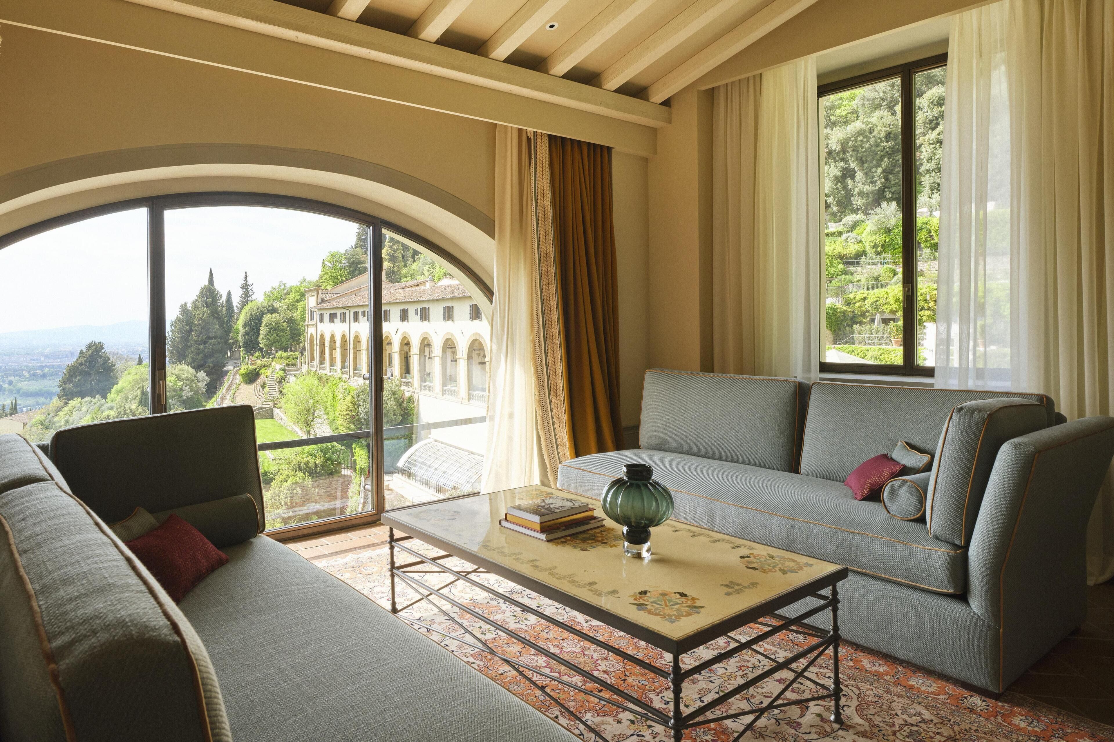 Una habitación con sofá, una mesita de centro y vistas a un edificio con arcos.