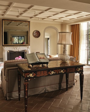 A room with a fireplace, a sofa, a table with a book, and a lamp. - Villa San Michele, A Belmond Hotel, Florence (Fiesole)