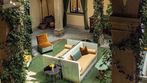 Un patio con un sofá, sillas y una mesa, rodeado de arcos y follaje.
