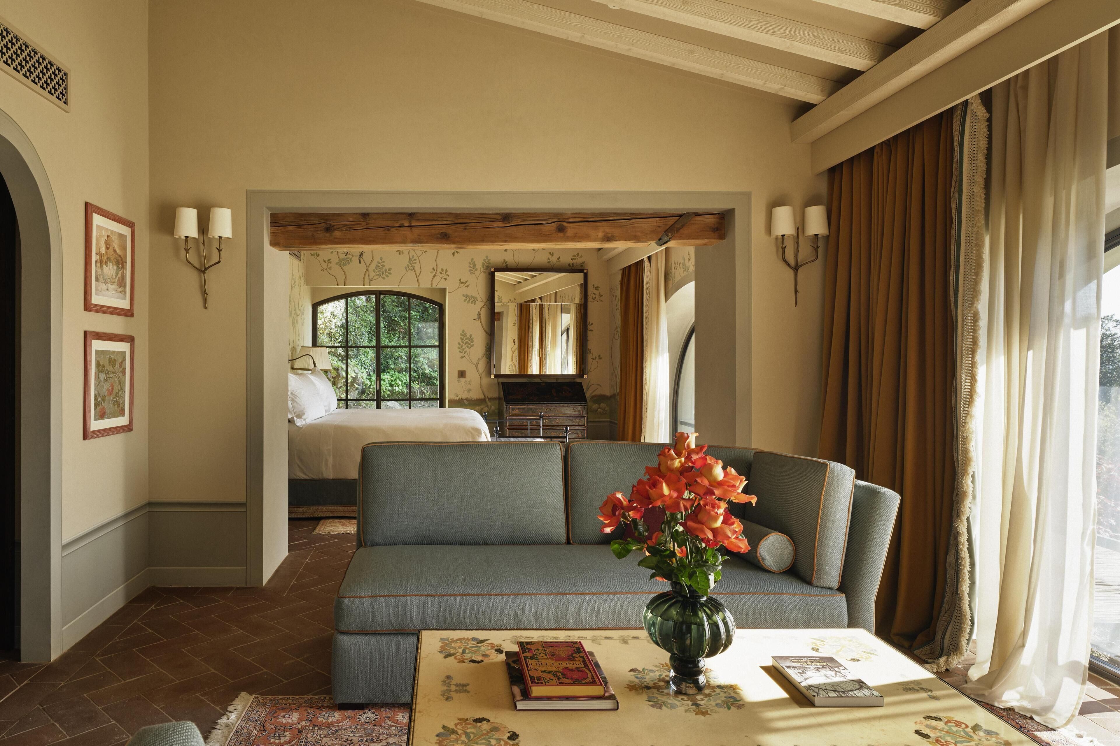 A room with a sofa, a vase with flowers, a book, and a remote control on a table.