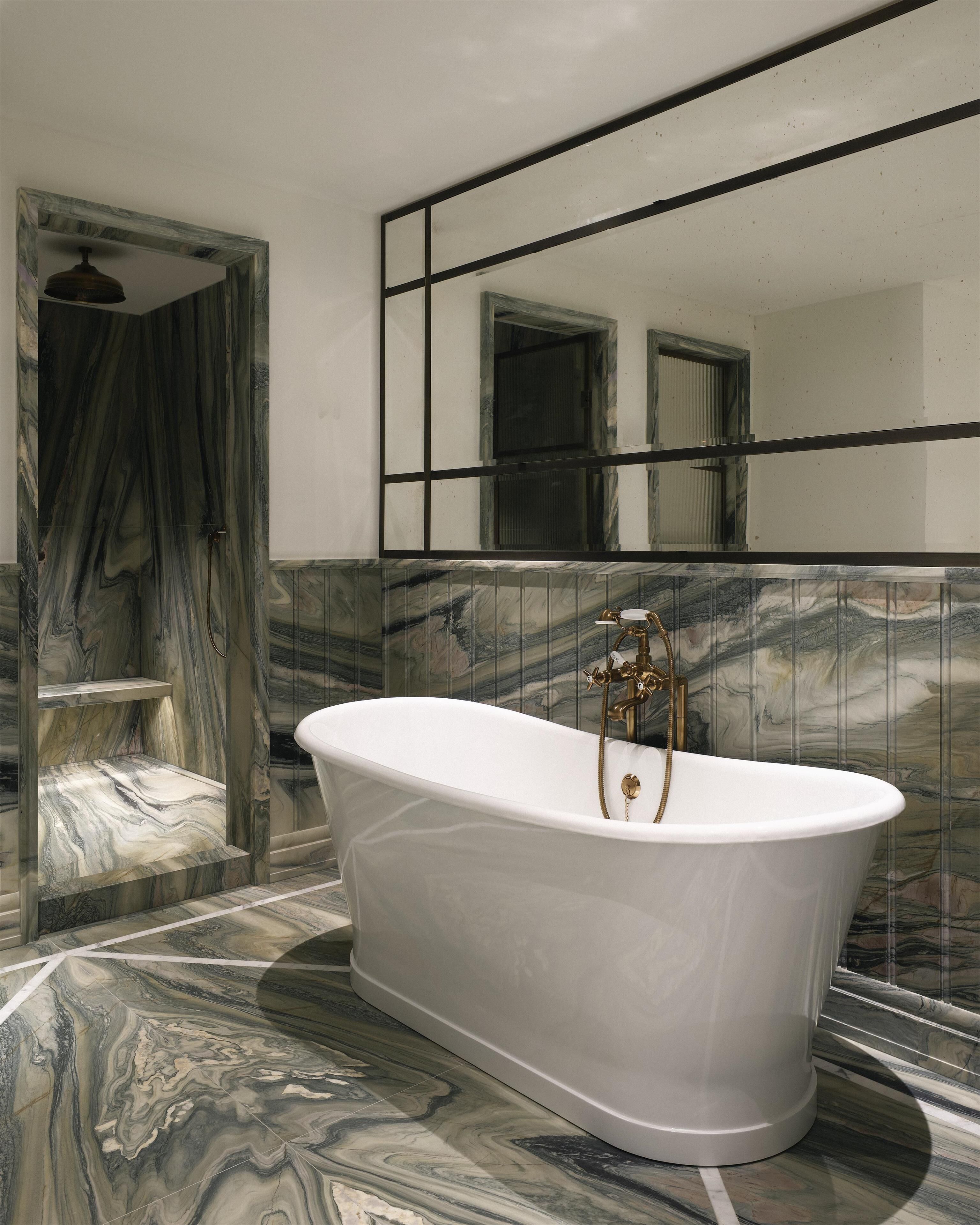 A bathroom with a freestanding bathtub, marble flooring, and a large mirror with a black frame.