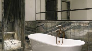 A bathroom with a freestanding bathtub, marble flooring, and a large mirror with a black frame.