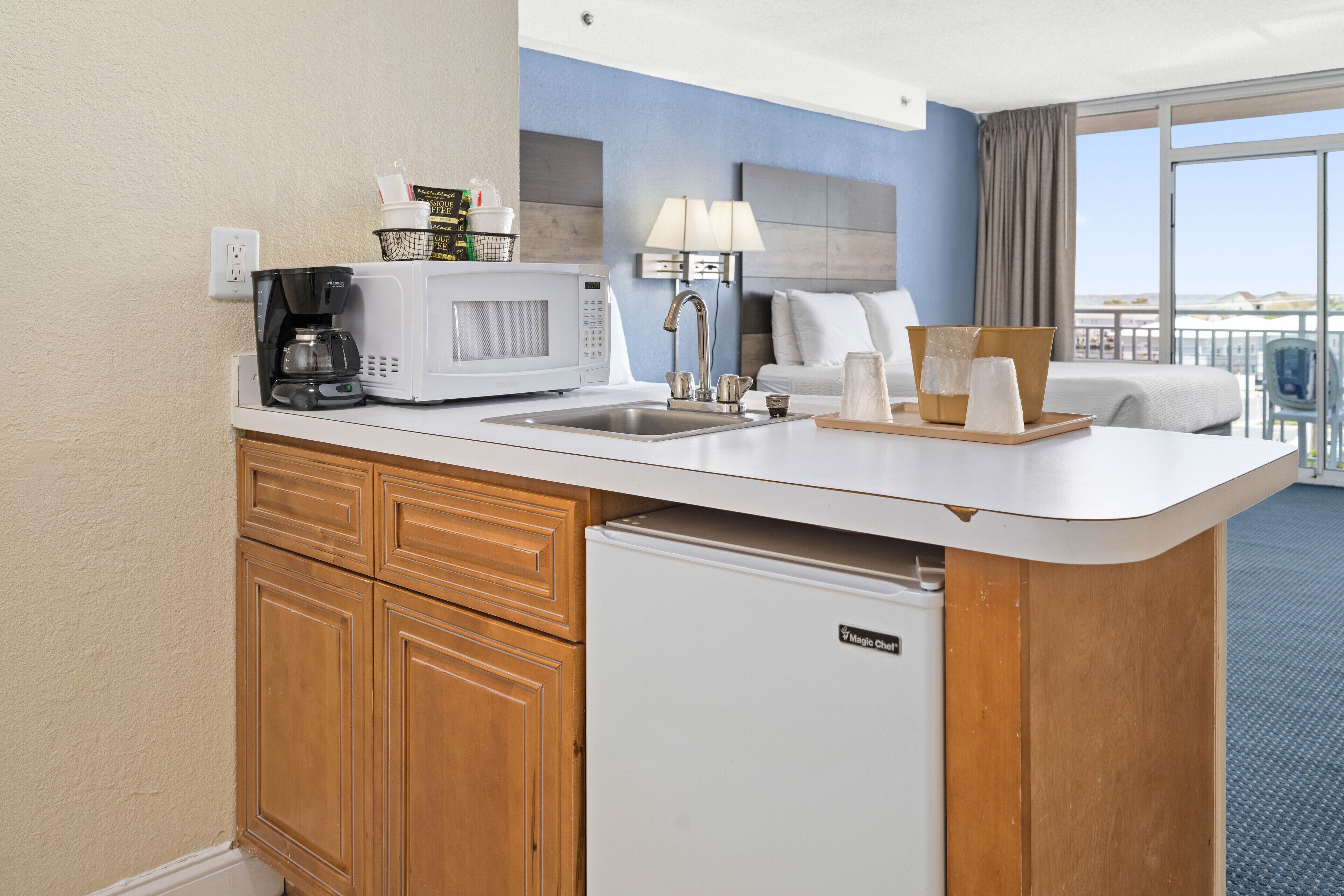 A compact hotel kitchenette with a microwave, coffee maker, and a small refrigerator.