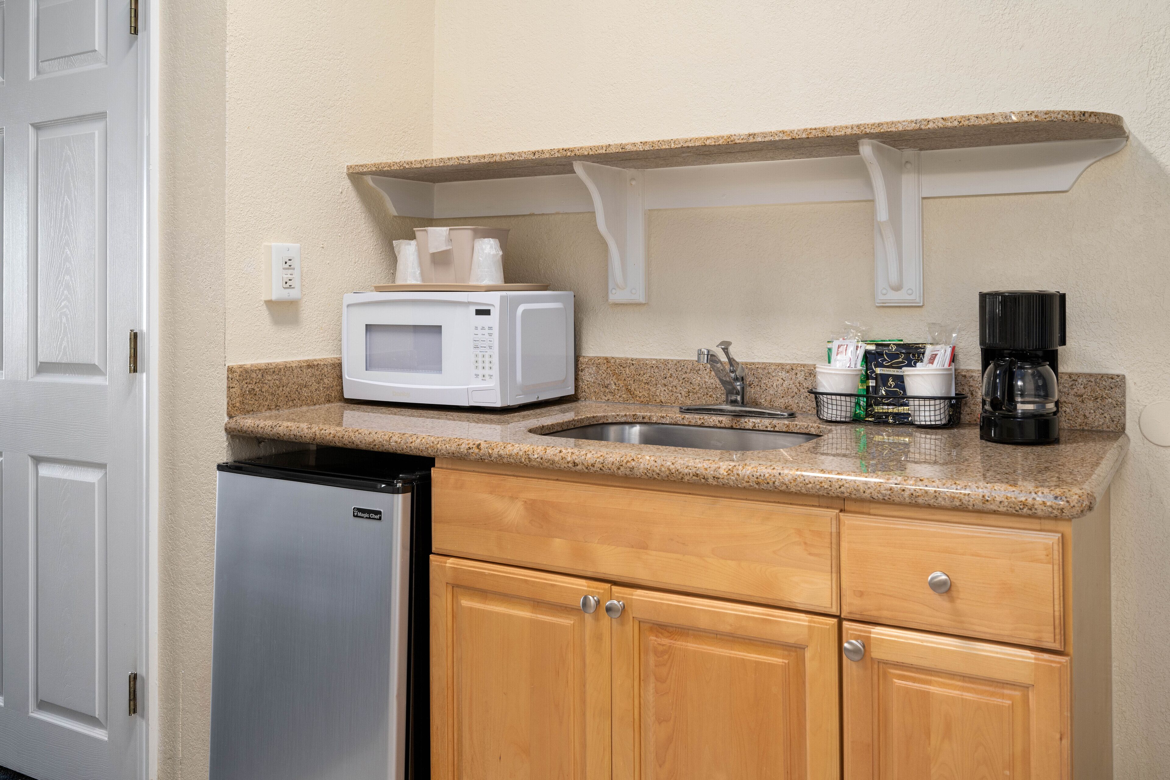 Una cocina compacta con microondas, cafetera y pileta.