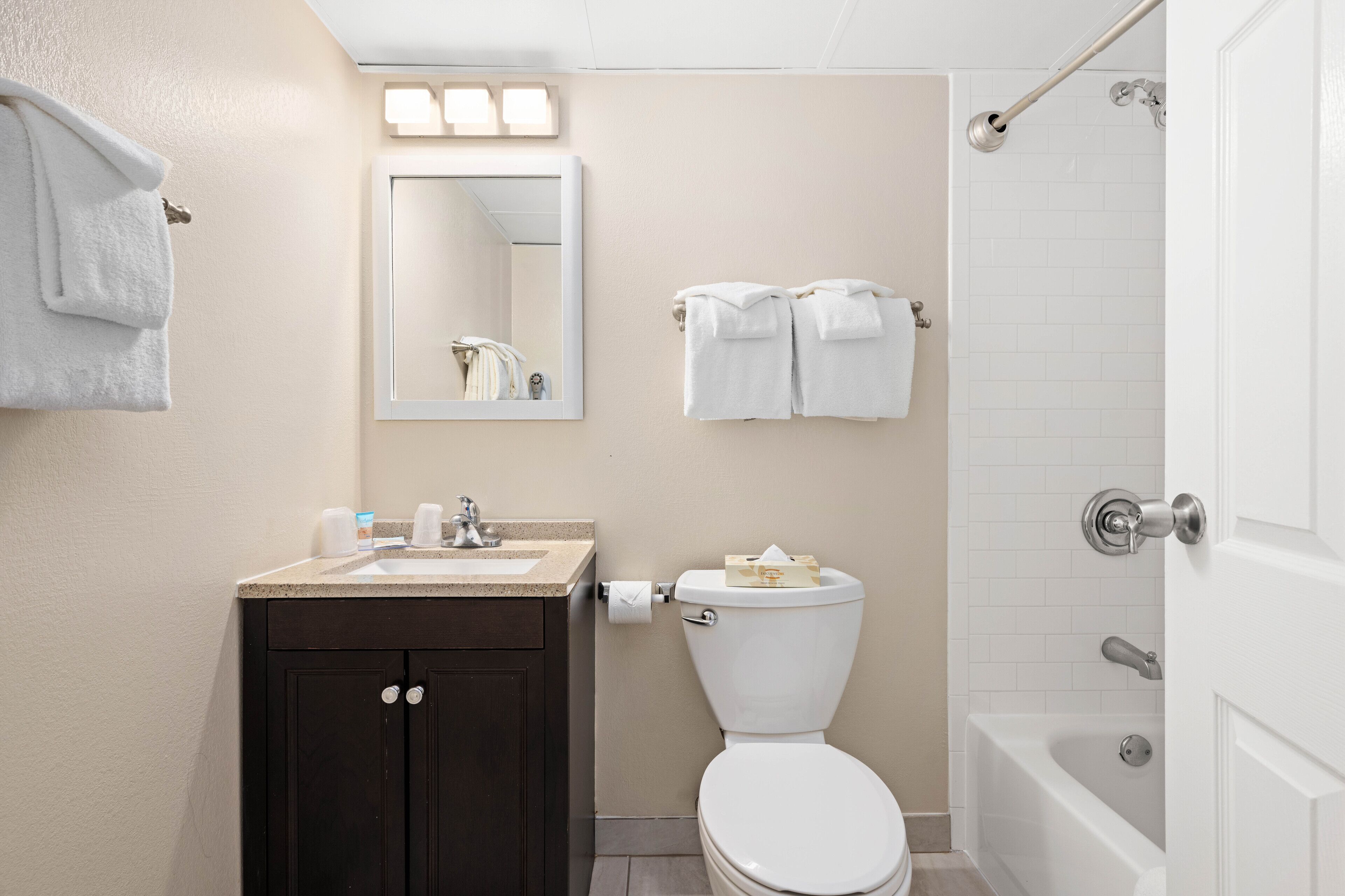 A bathroom with a sink, mirror, toilet, and bathtub.