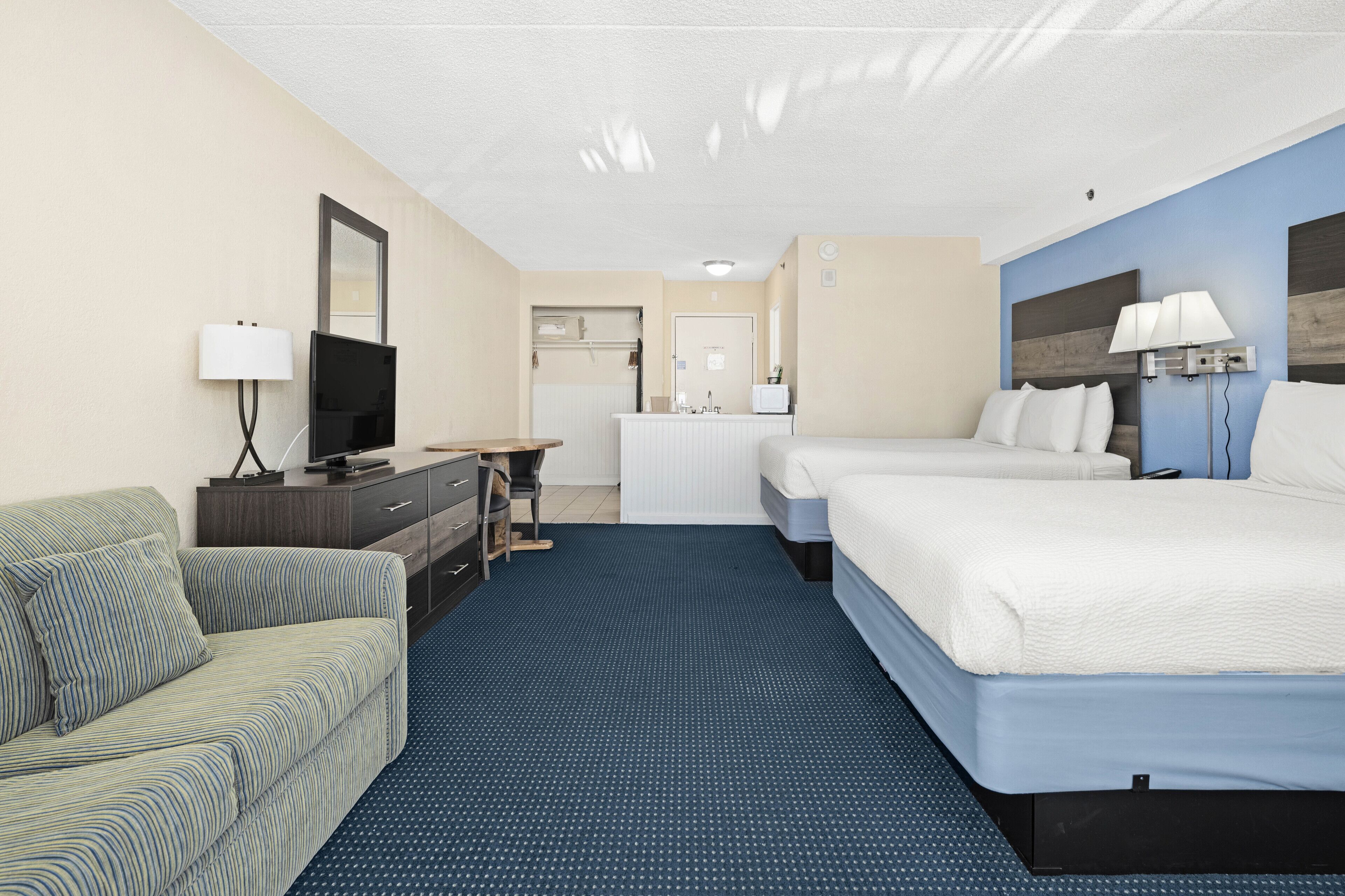 A hotel room with a bed, a sofa, a desk, a television, and a bathroom.