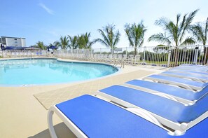 Relax by the pool surrounded by palm trees and lounge chairs.