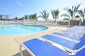 Relax by the pool surrounded by palm trees and lounge chairs.