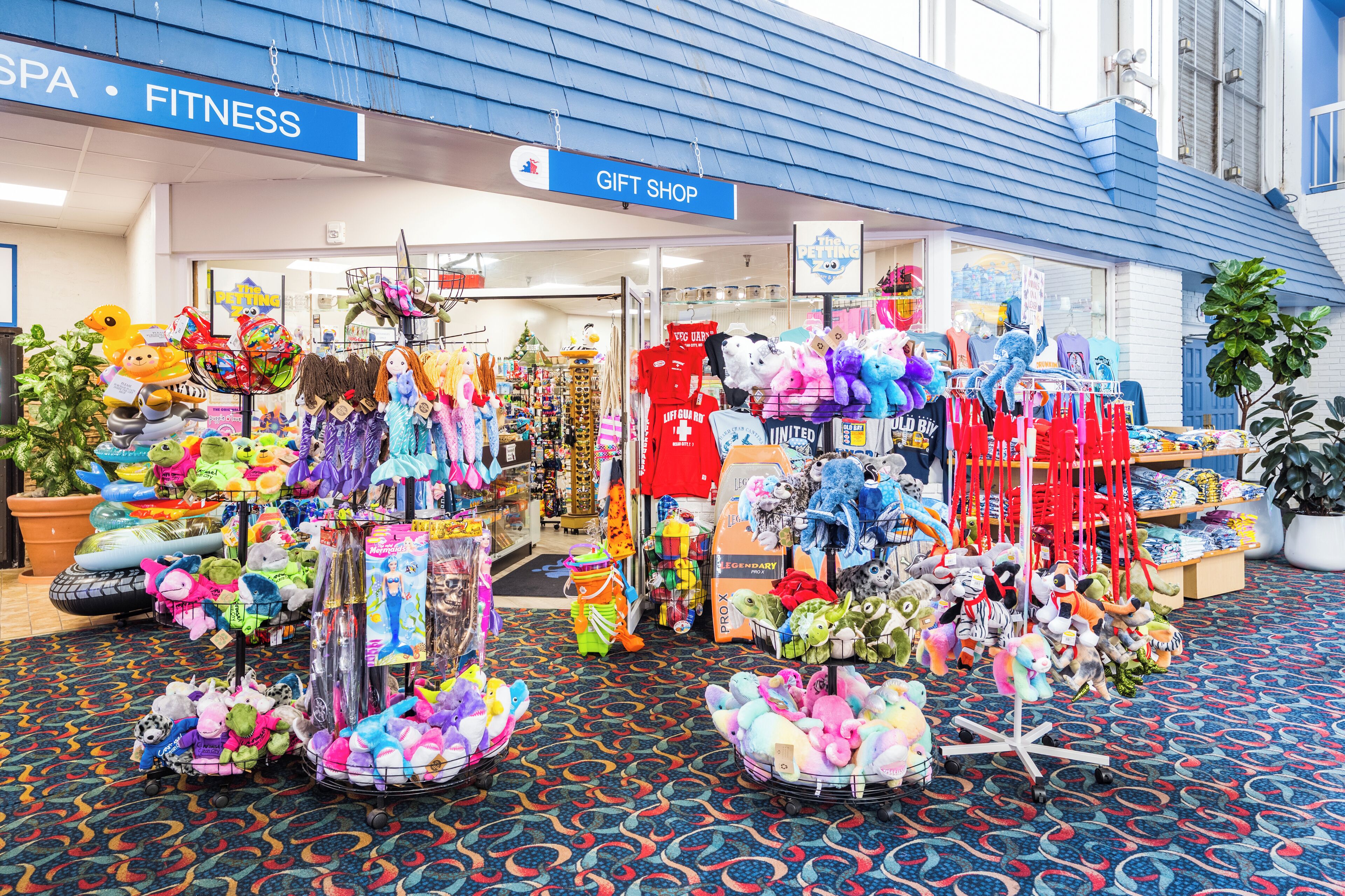 Una tienda de regalos con varios peluches y juguetes exhibidos en recipientes y estantes.