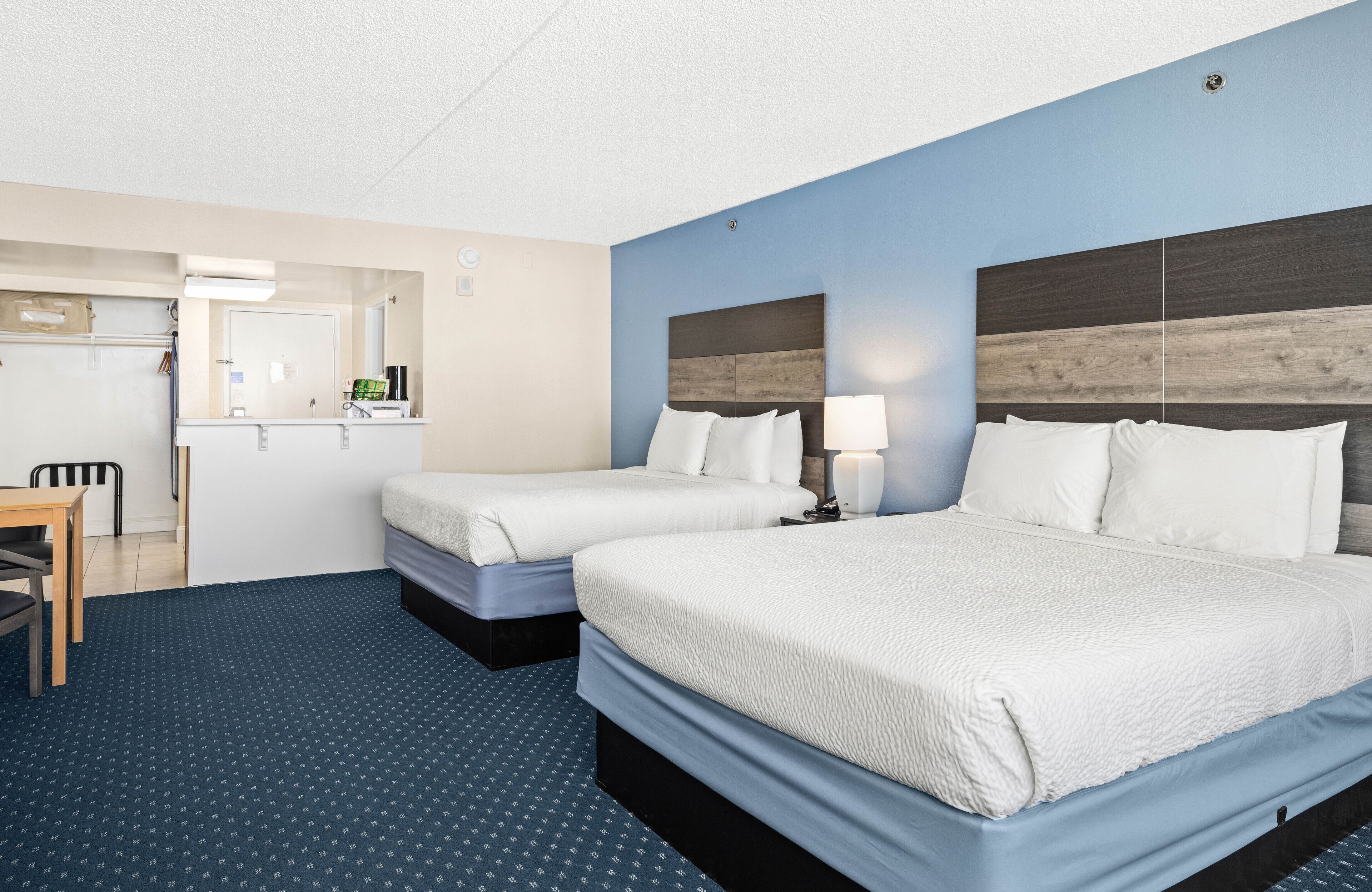 Habitación de hotel con dos camas, un escritorio y un espejo.