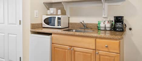 A compact kitchen with a microwave, coffee maker, and a sink.
