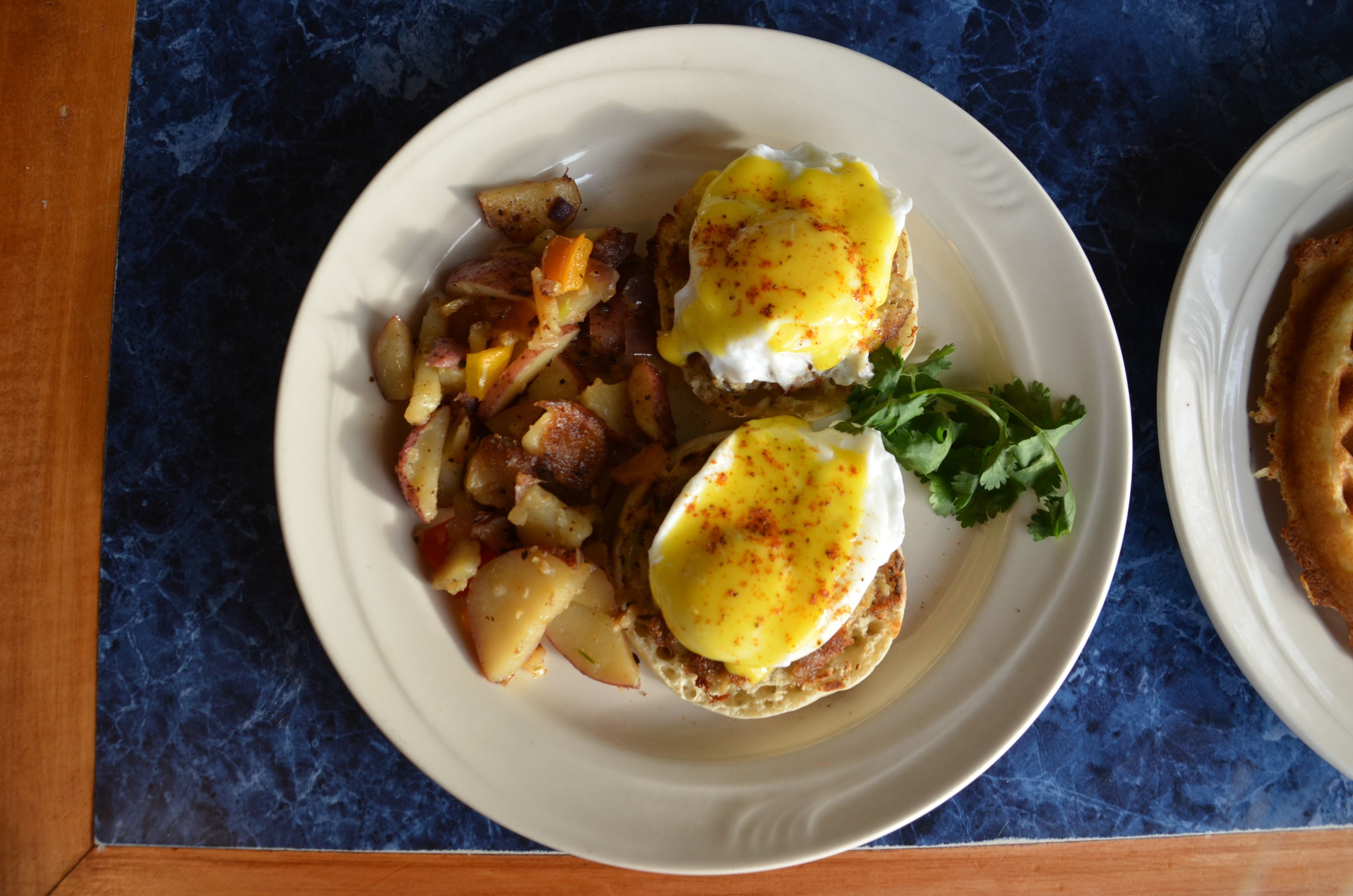 Ein Teller mit Eiern Benedict und Kartoffeln.