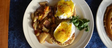 A plate with eggs benedict and potatoes.
