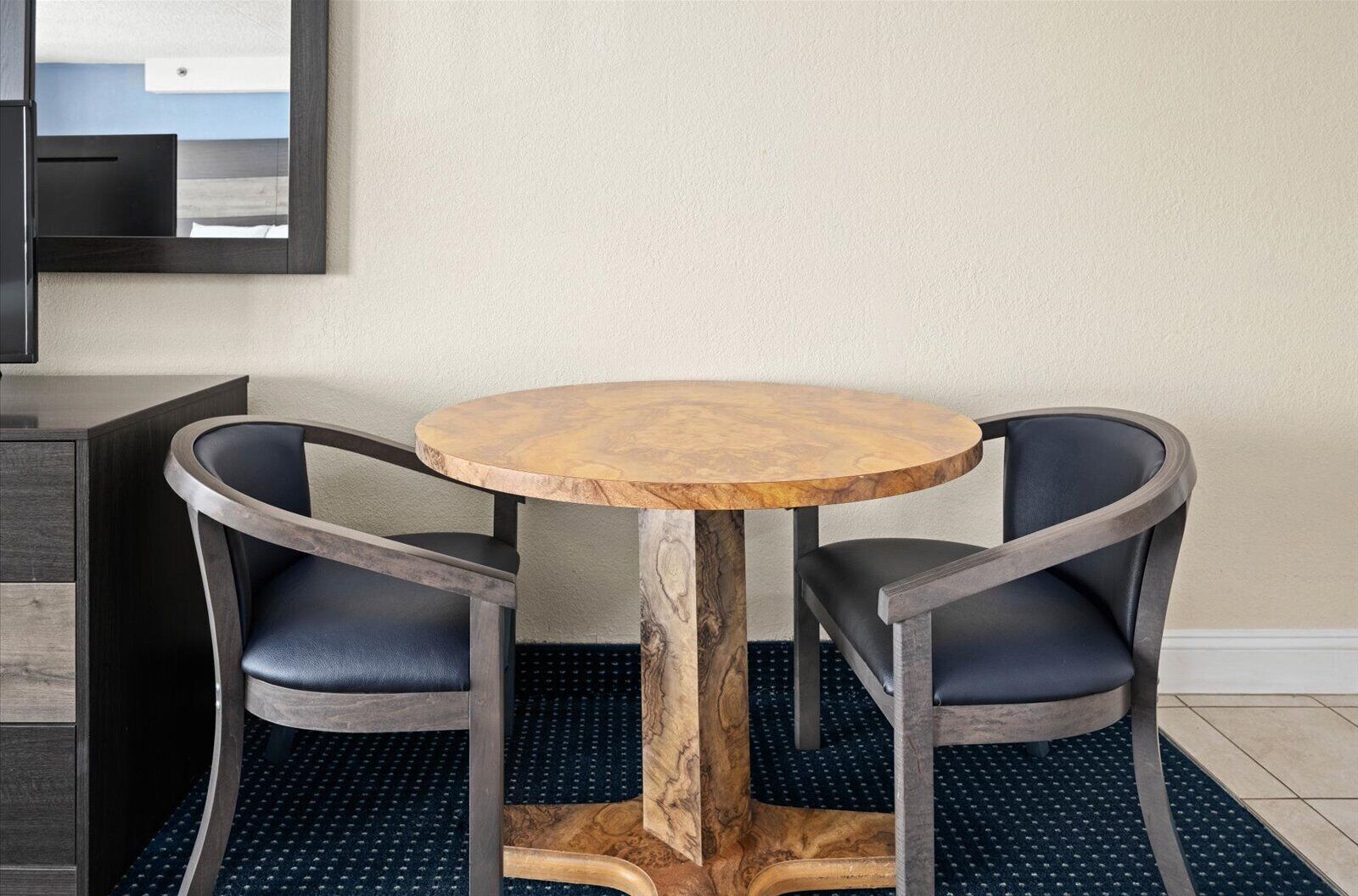 Una mesa redonda de madera con dos sillas de cuero oscuro.