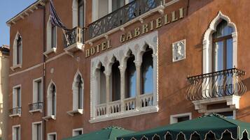A historic building with a sign reading 'HOTEL GABRIELLI,' featuring ornate balconies and a terrace with outdoor seating.