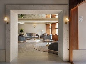 Un salon moderne avec un canapé d’angle, une table basse ronde et une vue sur la pièce adjacente grâce à une porte ouverte.