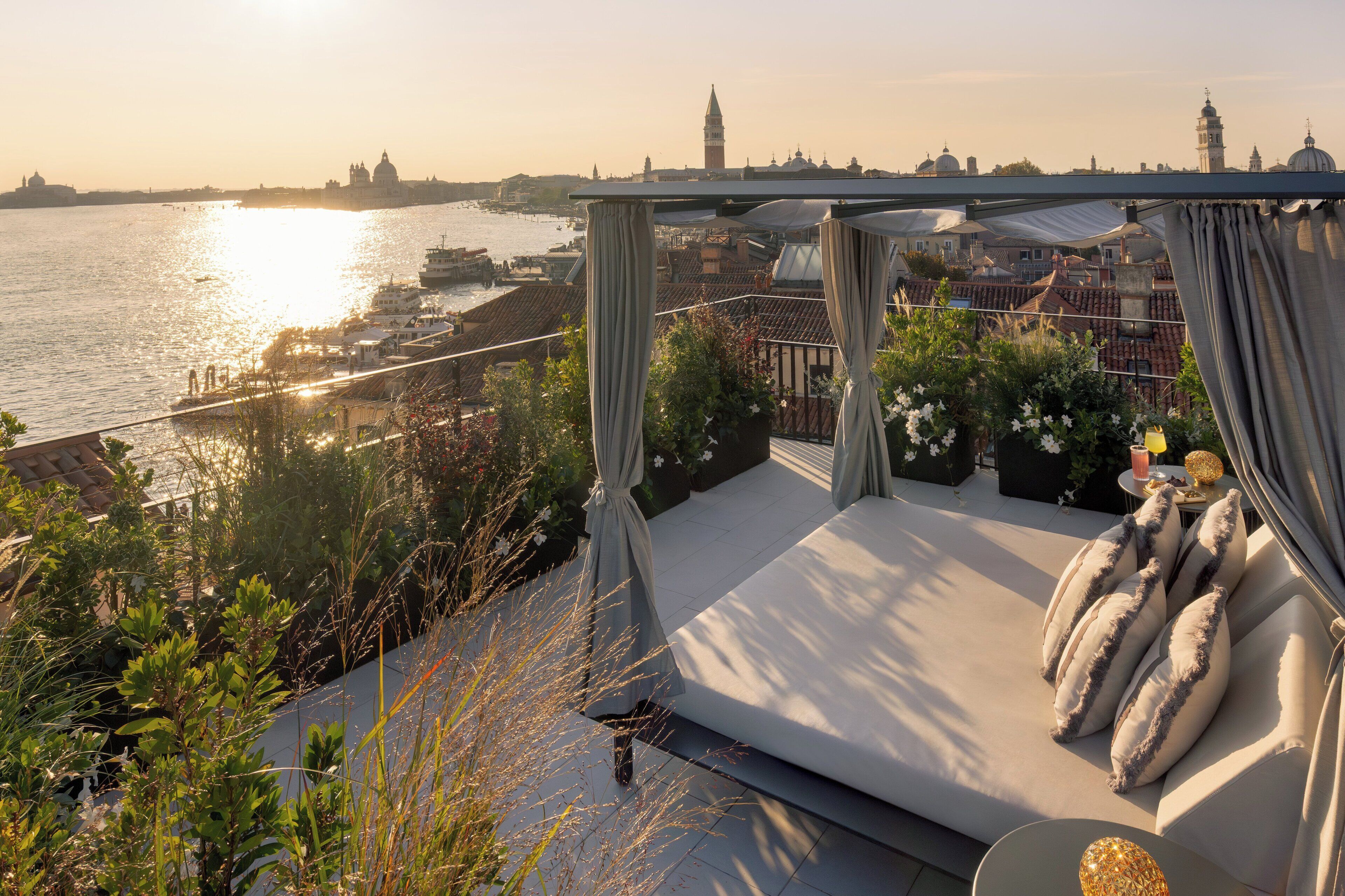 A balcony with a view of a river, boats, and city buildings.