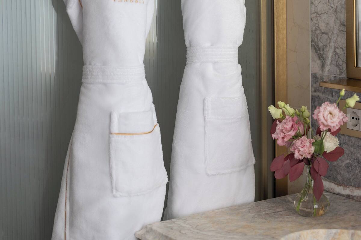 Deux tabliers blancs sont accrochés à des crochets, et l’inscription « HÔTEL GABRIEL VENEZIA » est clairement visible sur chacun d’eux.