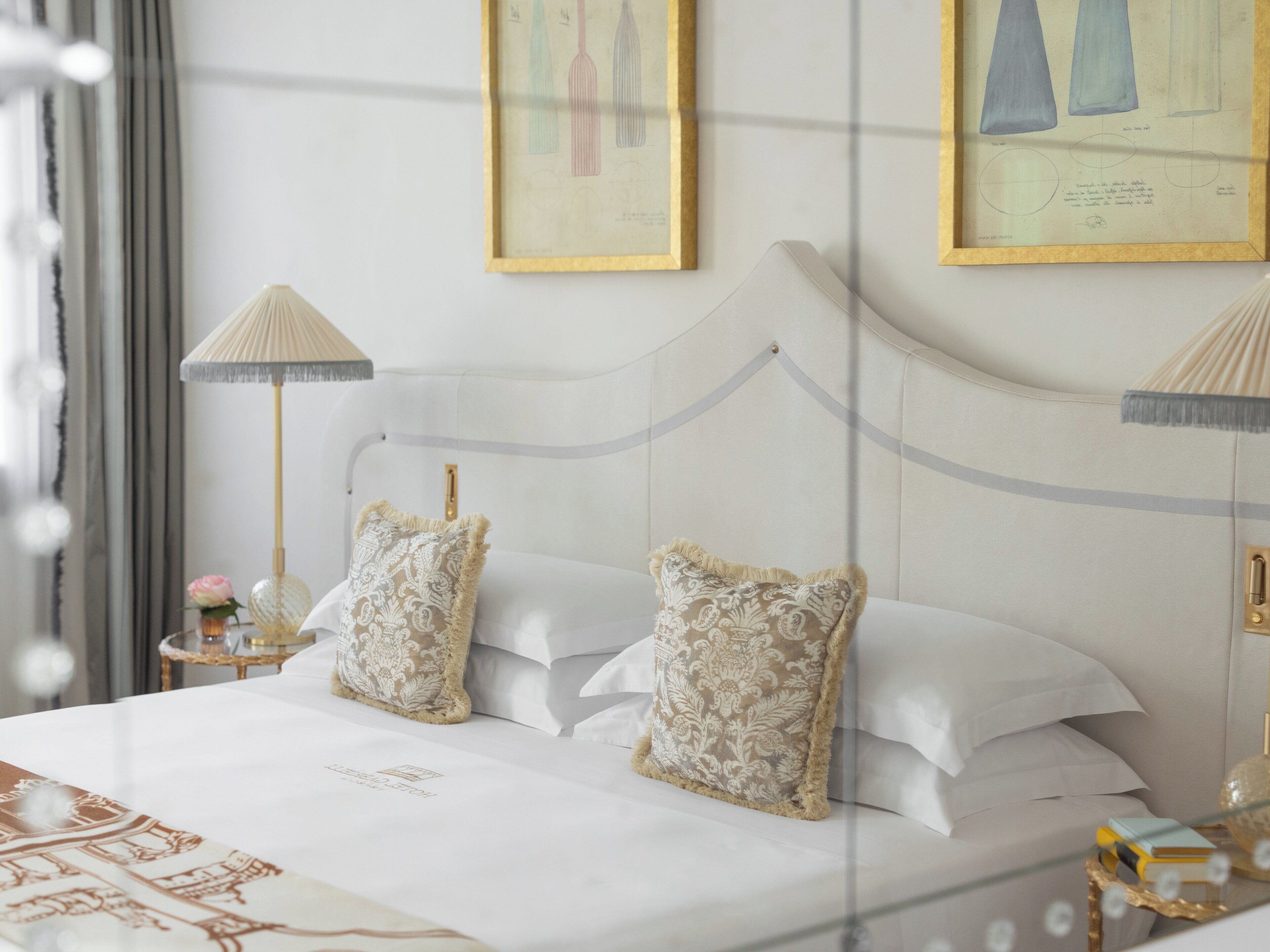 A neatly made bed with two decorative pillows, a bedside table with a lamp, and framed artwork on the wall.