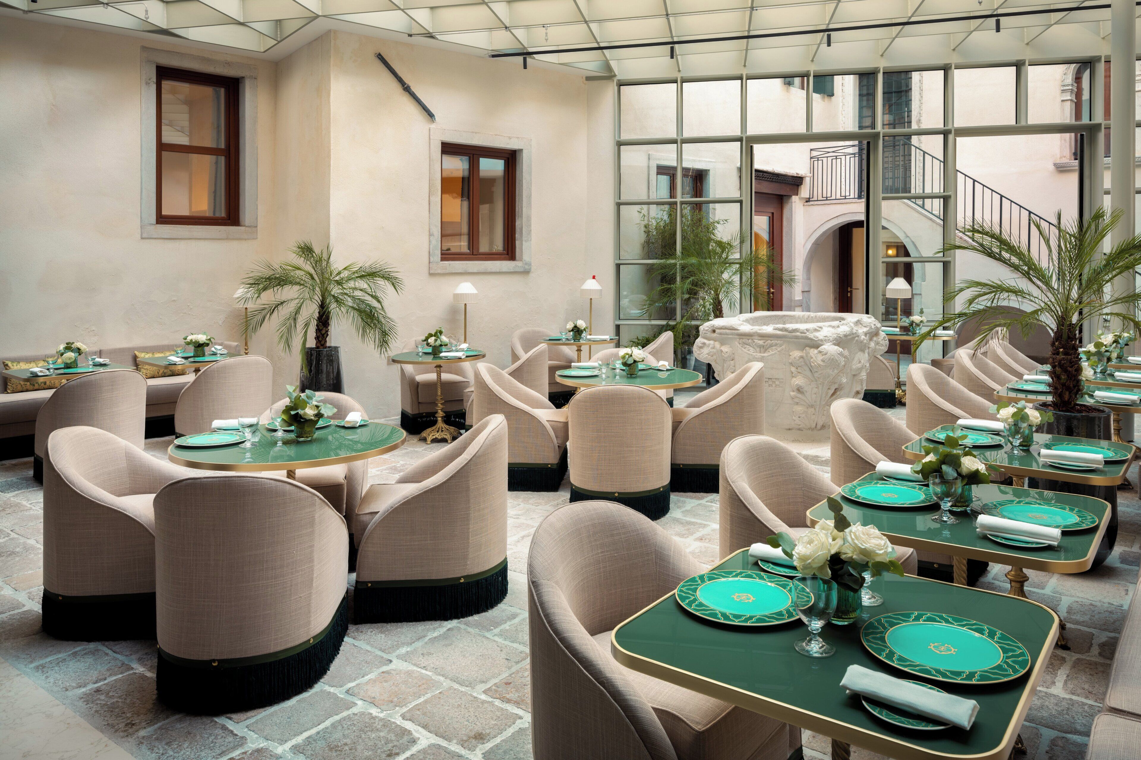 A restaurant with round tables, beige chairs, and green table settings.