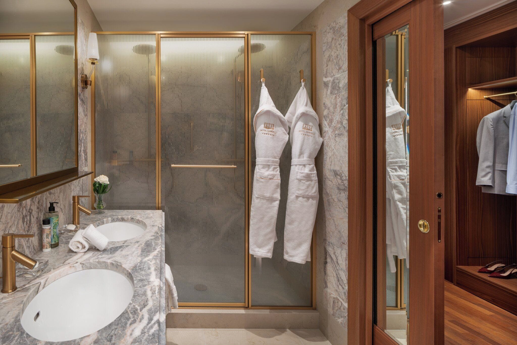 Une salle de bain moderne avec deux lavabos, une douche à parois de verre et un meuble-lavabo en bois doté d’un miroir.