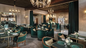 A dining area with green upholstered chairs, round tables, and chandeliers. - Hotel Gabrielli - Starhotels Collezione  (Venice)