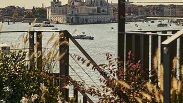 A view of a historic building with domes and a large bell tower across the water, with boats and a bridge in the foreground.