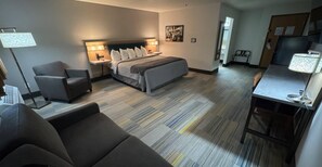 A hotel room with a bed, bedside tables, a desk, a chair, and a lamp.