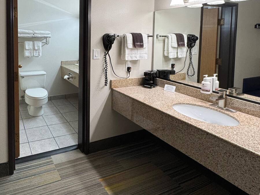 A hotel bathroom with a sink, mirror, towel rack, and hair dryer.