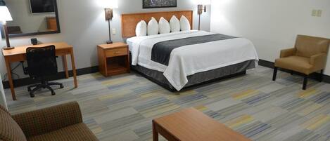Relax in a cozy space with a neatly made bed, desk, and comfortable chair.