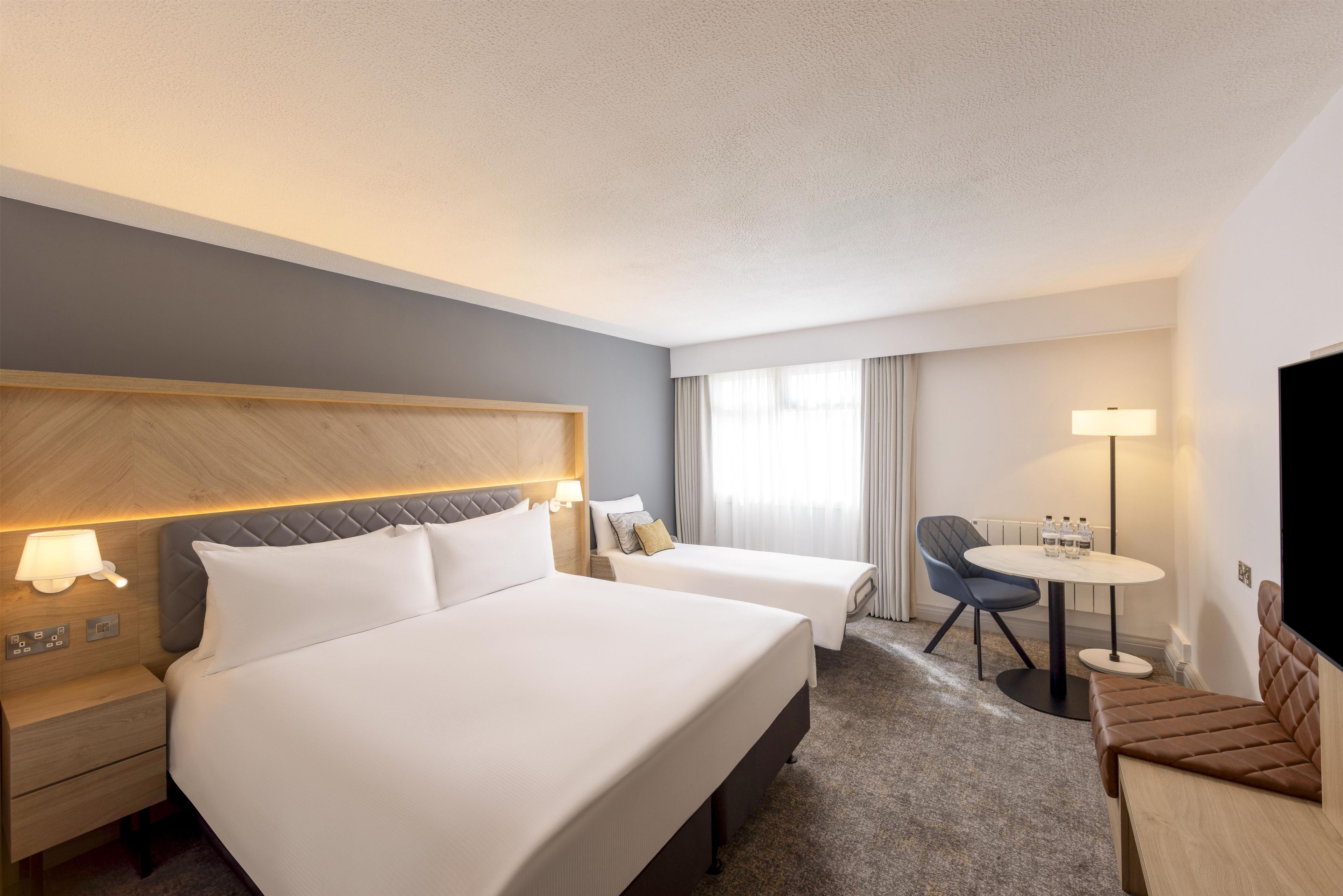 Hotellihuone, jossa on kaksi sänkyä, työpöytä, tuoli ja televisio.