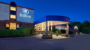 Ein Hilton Hotel mit auffälliger Beschilderung, überdachter Eingangspartei und gut beleuchteter Fassade.