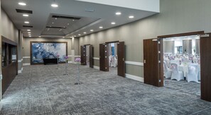 A spacious hotel corridor with multiple doors, a reception area, and a banquet setup. - Hilton London Watford (Watford)