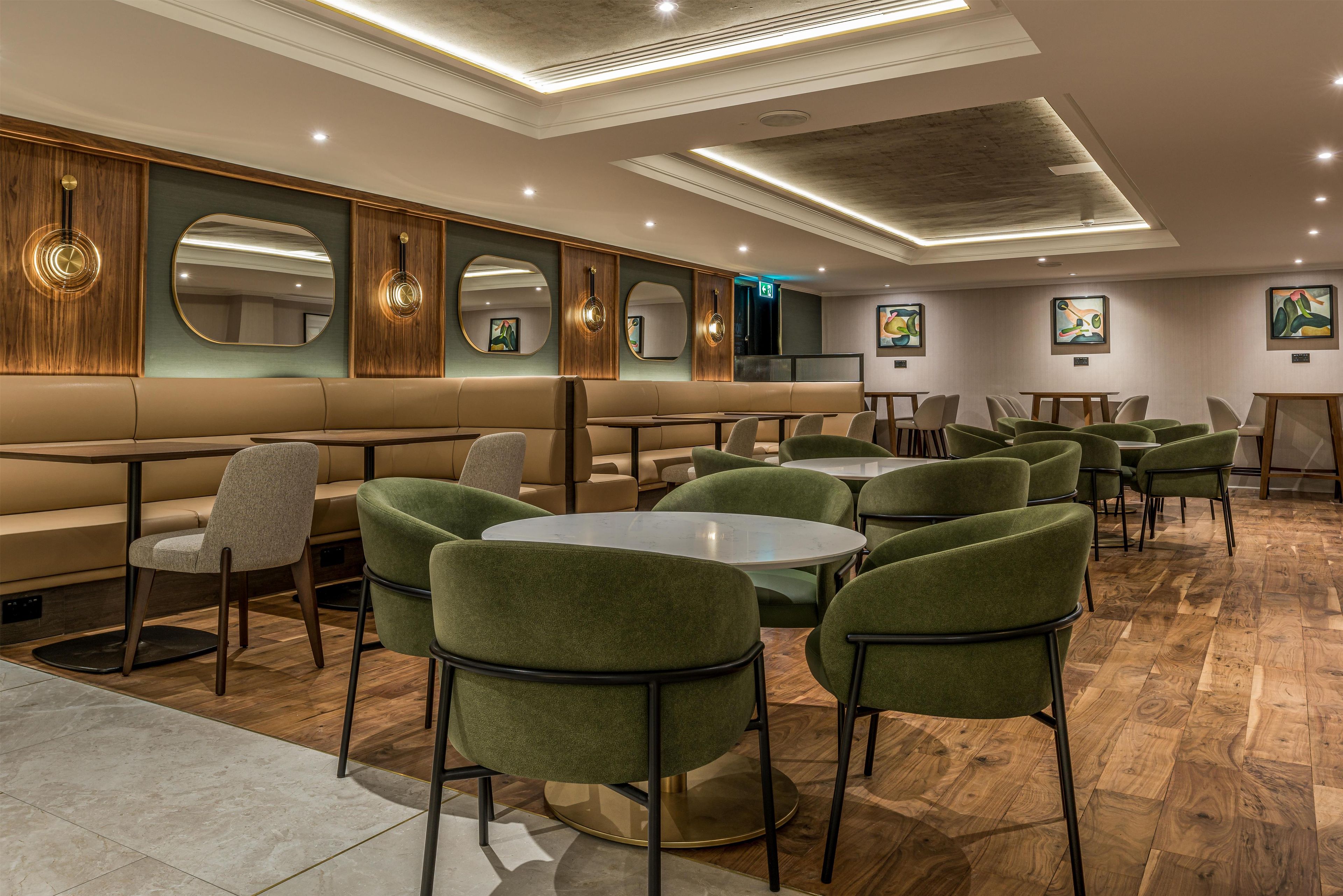 Et moderne restaurantmiljø med båse og runde borde, trægulv og billeder på væggene.