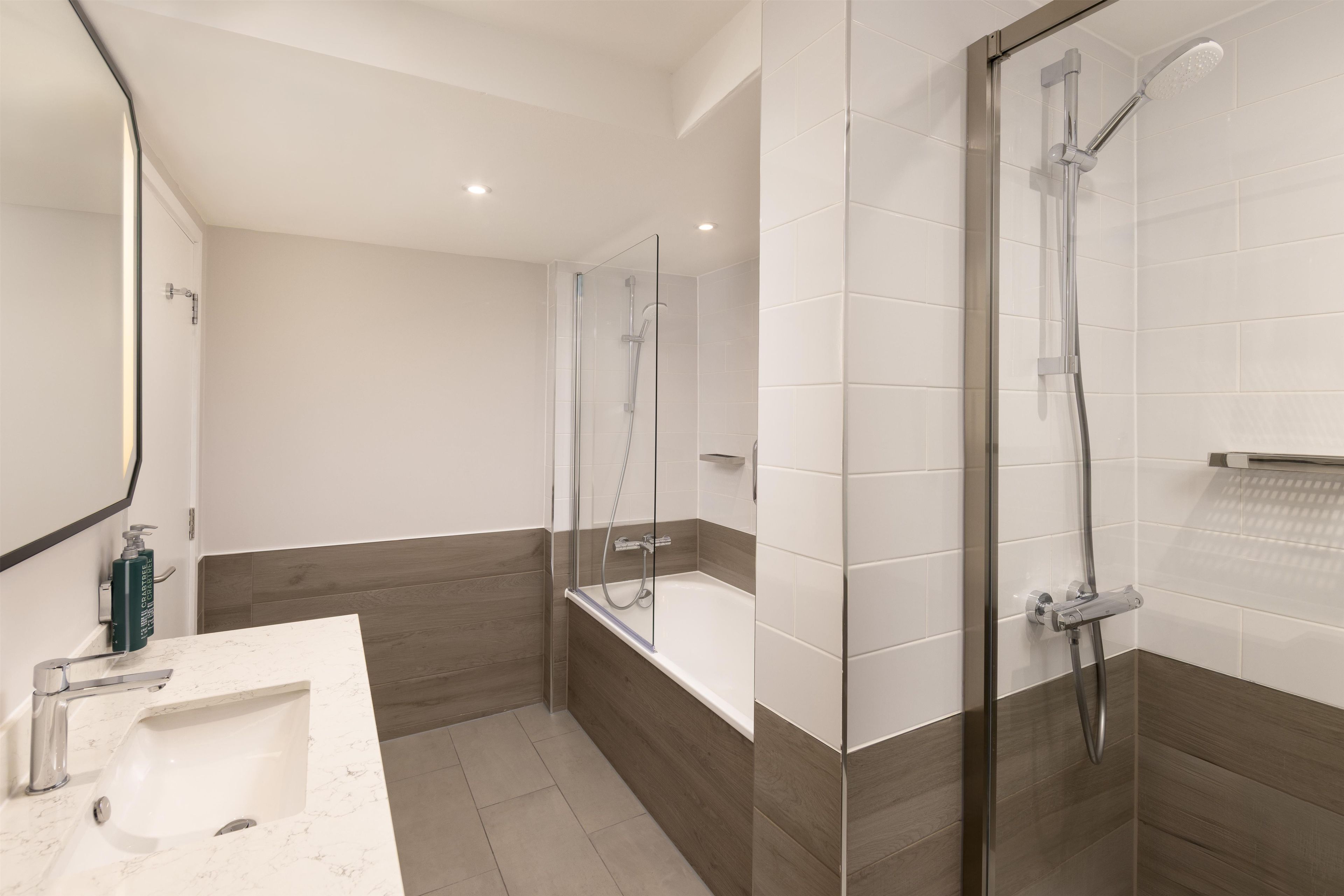 Une salle de bain moderne avec une douche à parois de verre, une baignoire et un lavabo en marbre.