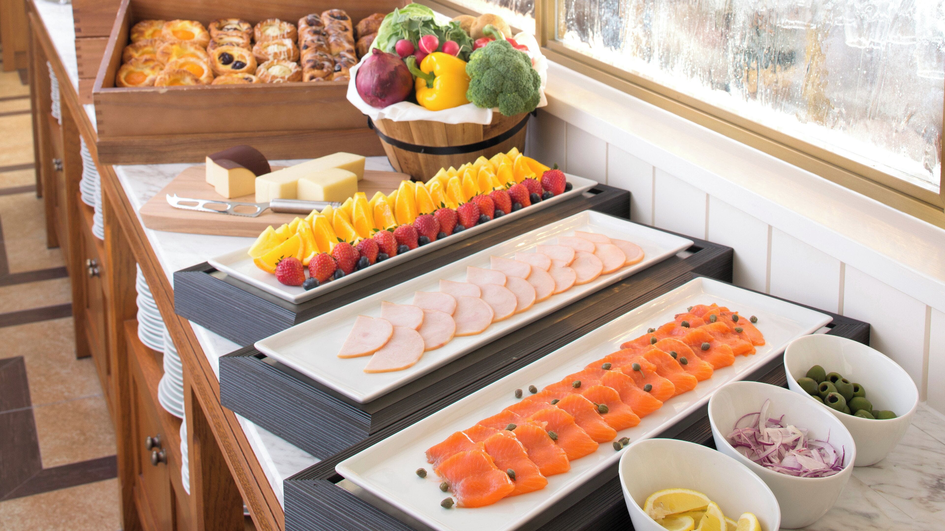 A buffet with various food items including fruits, vegetables, and deli slices.