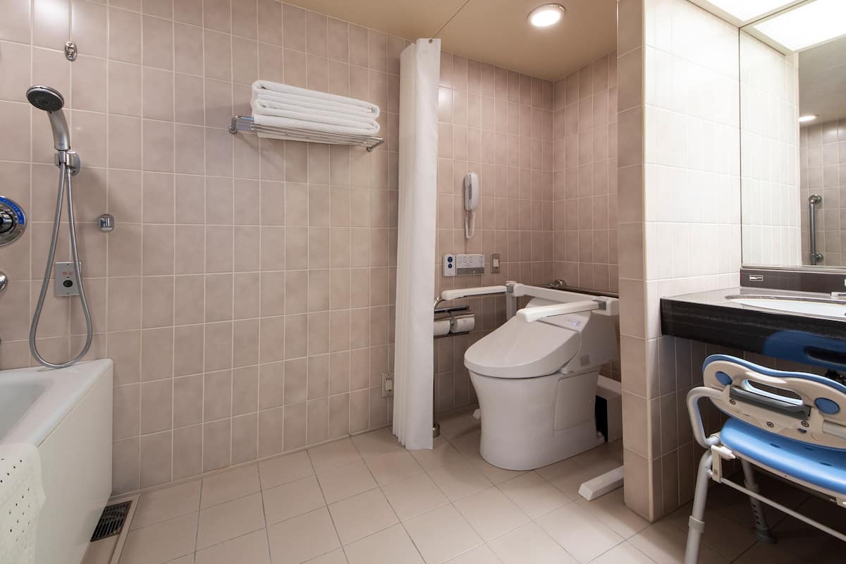 A modern bathroom with a shower, toilet, and a wheelchair-accessible bench.