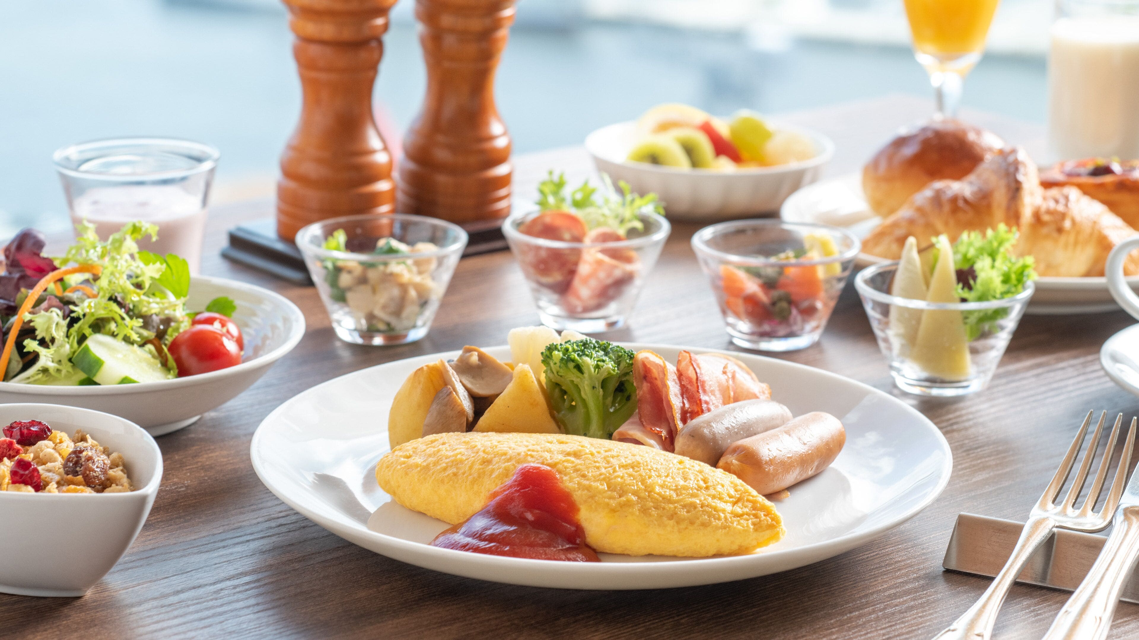 A breakfast setting with various dishes including eggs, bacon, and vegetables on a wooden table.
