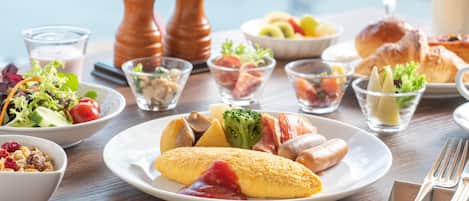 A breakfast setting with various dishes including eggs, bacon, and vegetables on a wooden table.