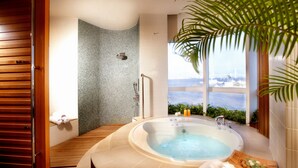 Un baño con bañera, ducha y vistas al mar.