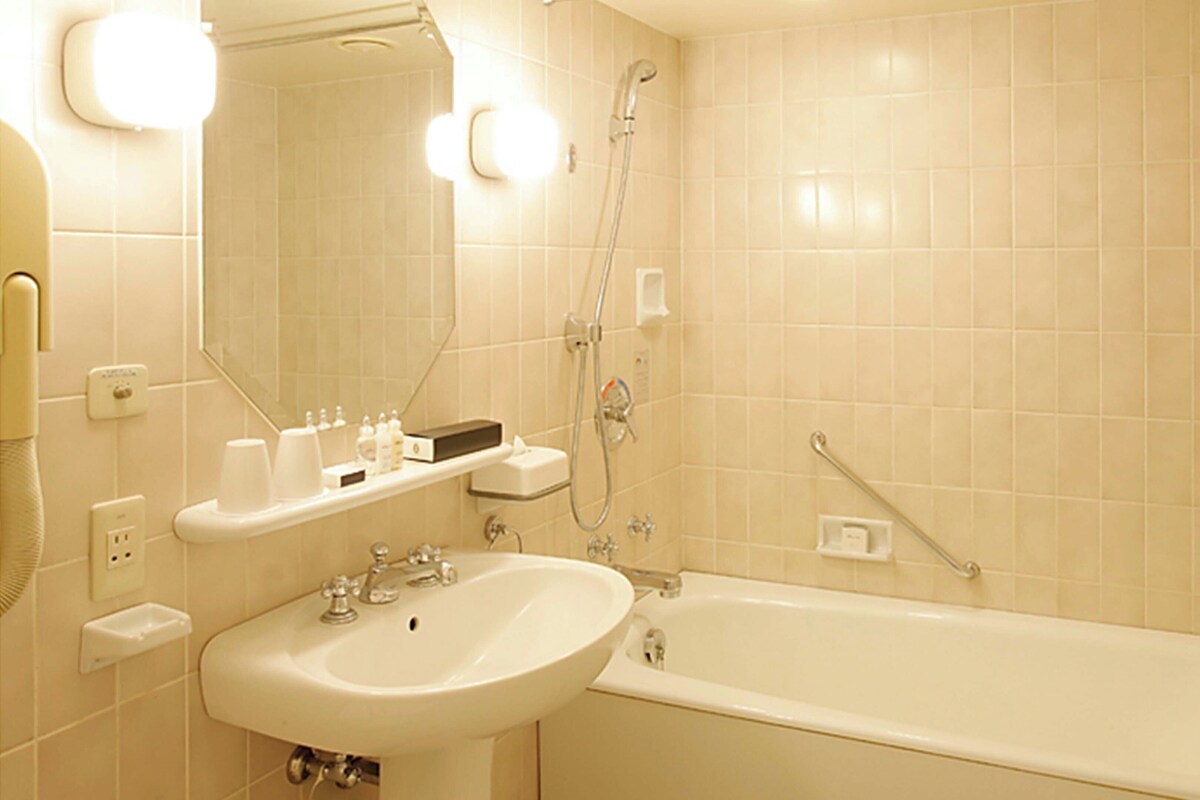 A bathroom with a sink, mirror, shower, and a towel rack.